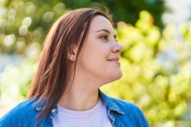 Young beautiful plus size woman smiling confident looking to the side at park