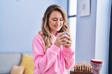 Young woman drinking coffee standing at home