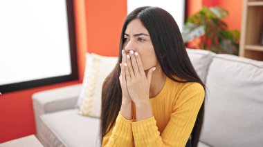 Evdeki kanepede oturan genç ve güzel İspanyol kadın stresli.