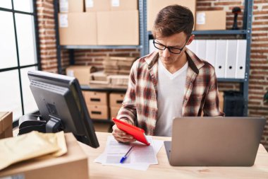 Young man ecommerce business worker using laptop and touchpad working at office