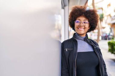 Afro-Amerikalı kadın gülümsüyor. Kendinden emin bir şekilde caddeye bakıyor.