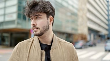 Latin kökenli genç adam ciddi bir ifadeyle sokağa bakıyor.