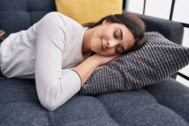 Young beautiful hispanic woman lying on sofa sleeping at home