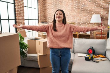 Young hispanic woman standing with arms open at new home