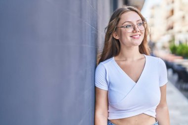 Young blonde woman smiling confident looking to the side at street