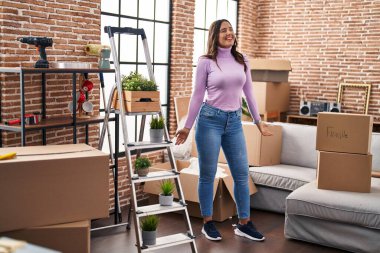 Young hispanic woman smiling confident dancing at new house