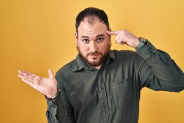 Ayrıca sarı arka planda dikilen sakallı İspanyol bir adam. Avuç içinin açık olması, fotokopi alanını göstermesi ve alnını işaret etmesi kafasını karıştırmış. Bunu bir düşün.. 