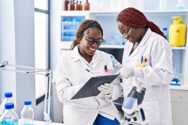 African american women scientist holding test tube writing on document at laboratory
