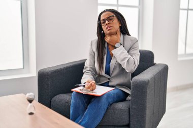 Örgülü genç Afro-Amerikalı danışma ofisinde çalışıyor. Ağrılı boynuna dokunuyor. Grip, mantar ve enfeksiyon yüzünden boğazı ağrıyor. 
