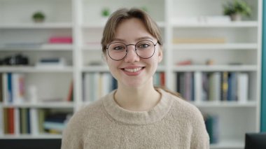 Young blonde woman student smiling confident standing at library university
