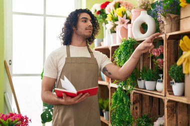 Çiçekçide kitap okuyan genç Latin bir çiçekçi.