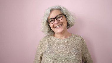 Middle age woman with grey hair smiling confident over isolated pink background