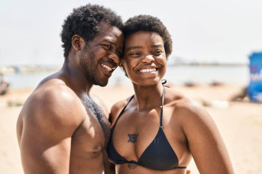 African american man and woman couple wearing swimsuit hugging each other at seaside