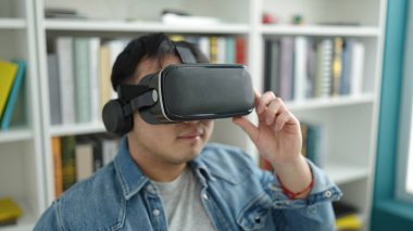 Kütüphanede sanal gerçeklik gözlüğü kullanan Çinli genç bir öğrenci.