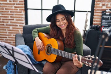 Genç İspanyol kadın müzisyen müzik stüdyosunda klasik gitar çalıyor.