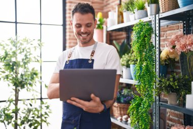 Çiçekçiye dizüstü bilgisayar kullanarak gülümseyen İspanyol bir çiçekçi.
