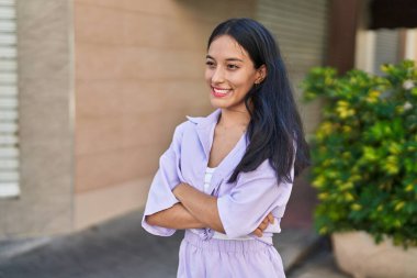 Sokakta kollarını kavuşturmuş genç, güzel İspanyol bir kadın.