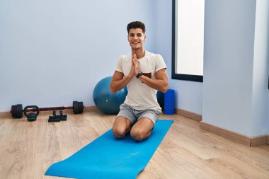 Spor merkezinde yoga eğitimi alırken gülümseyen İspanyol genç adam.