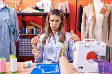 Atölyedeki İspanyol kadın terzinin tasarımcısı üzgün ve üzgün görünüyor, parmaklarıyla yönü gösteriyor, mutsuz ve depresif.. 