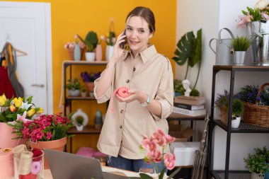 Çiçekçide elinde dantelle akıllı telefondan konuşan beyaz kadın çiçekçi.