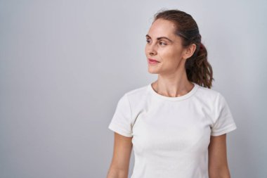 Güzel esmer kadın izole edilmiş arka planda duruyor. Gülümsüyor, yan tarafa bakıyor ve düşünüyor.. 