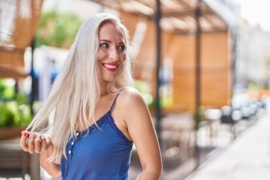 Young blonde woman smiling confident looking to the side at street