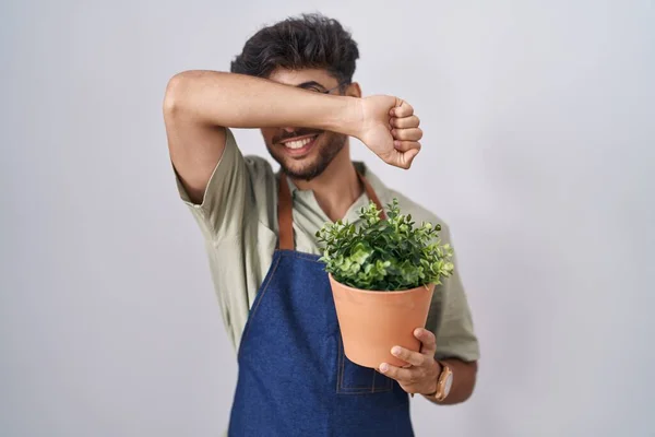 一个阿拉伯男人 留着胡子 拿着绿色的花盆 开心地笑着玩着 用手拿着脸看了看竹子 很惊讶也很兴奋 — 图库照片