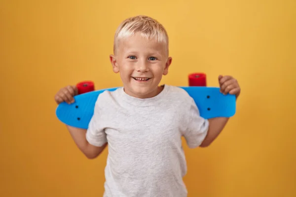笑顔で大声で笑いながらスケートを保持している小さな白人の男の子のために面白いクレイジー冗談 — ストック写真