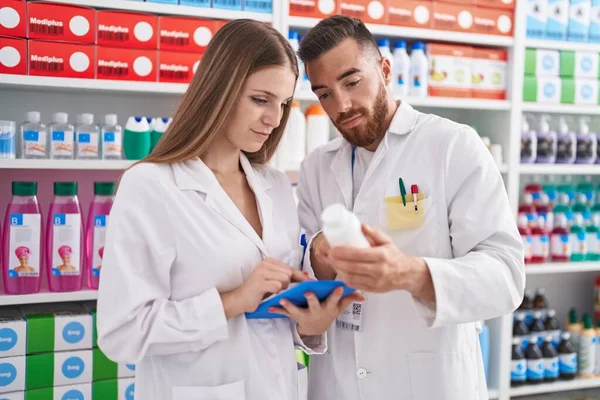 薬局で錠剤瓶を保持タッチパッドを使用する男性と女性の薬剤師 — ストック写真
