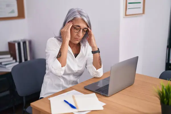 中年白发女商人在办公室使用笔记本电脑感到压力 — 图库照片