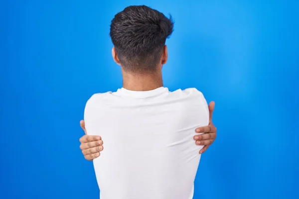 Hispánský Teenager Stojící Nad Modrým Pozadím Šťastně Objímající Pozpátku Self — Stock fotografie