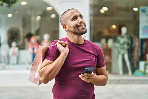 Young Latin Man Using Smartphone Holding Shopping Bag Street — Stok fotoğraf