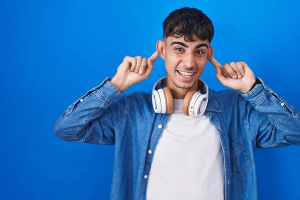 Young Hispanic Man Standing Blue Background Smiling Pulling Ears Fingers — Stock Photo, Image