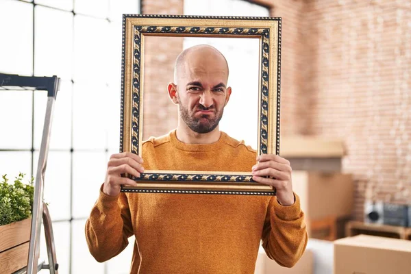 年轻的秃头男人带着胡子搬到一个新家 把脸放在老式的镜框里 毫无头绪和困惑的表情 怀疑概念 — 图库照片