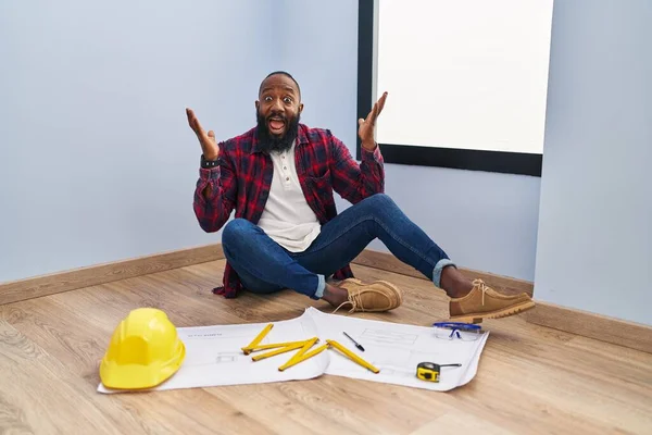 Hombre Afroamericano Sentado Suelo Una Casa Nueva Mirando Los Planos — Foto de Stock
