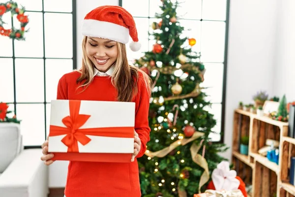 Νεαρή Λευκή Γυναίκα Ξεπακετάρει Δώρο Στέκεται Δίπλα Στο Χριστουγεννιάτικο Δέντρο — Φωτογραφία Αρχείου