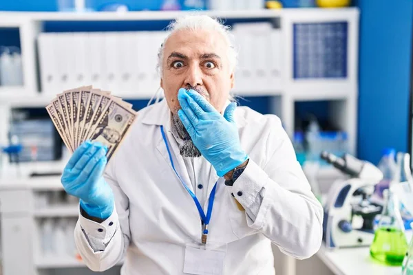 手で口を覆うお金を持っている科学研究所で働く白髪の中年の男は ショックを受け 間違いを恐れています 驚きの表情 — ストック写真
