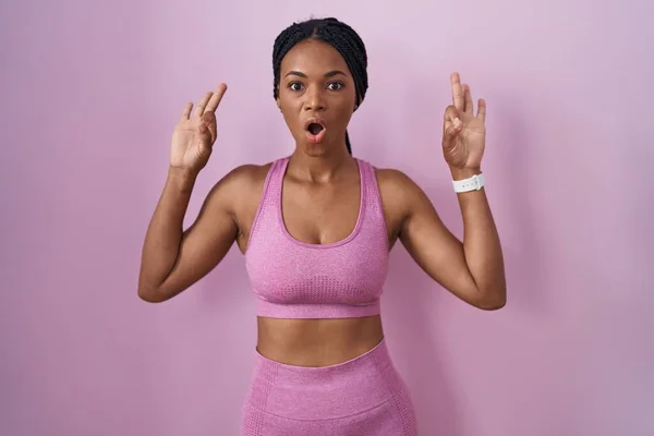 Африканская Американка Косичками Спортивной Одежде Розовом Фоне Выглядит Удивленной Шокированной — стоковое фото