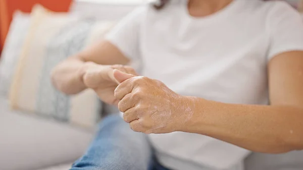 Middle Age Hispanic Woman Applying Skin Treatment Hand Sitting Sofa — Stock Photo, Image