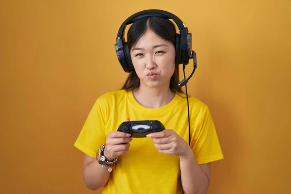 中国的年轻女子在玩电子游戏 手握控制器 面带微笑地鼓起双颊 气喘吁吁的嘴 疯狂的表情 — 图库照片