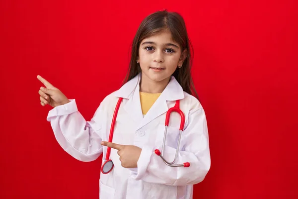 Malá Hispánka Doktorské Uniformě Stetoskopu Usmívá Dívá Kameru Ukazující Oběma — Stock fotografie