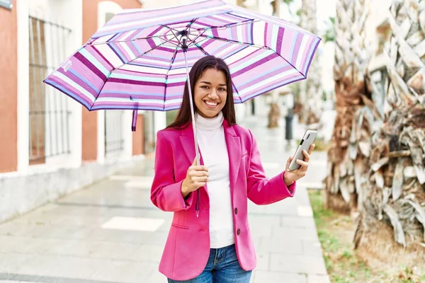 Young Latin Woman Using Smartphone Holding Umbrella Street — Stock Fotó