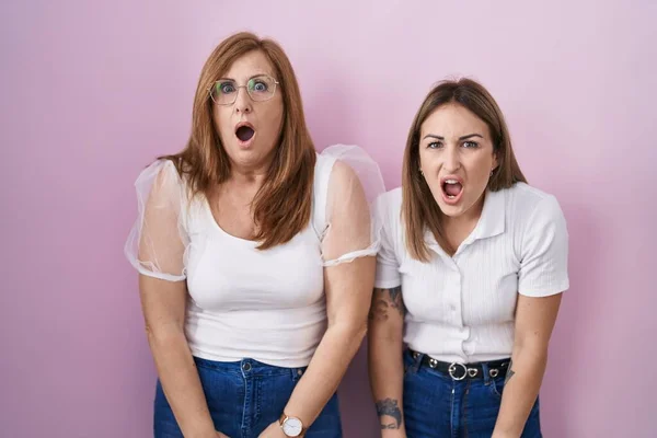 西班牙裔母亲和女儿穿着宽松的白色T恤 背景是粉色的 她们害怕 恐惧和兴奋的脸 — 图库照片