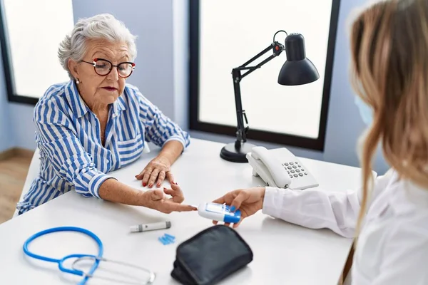 stock image Senior grey-haired woman patient having medical consultation measuring glucose at clinic