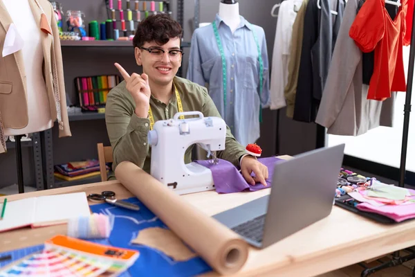 年轻的非二元男装制造商设计师在视频通话中带着笔记本电脑微笑 手指手画脚地指向旁边 — 图库照片