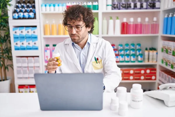 Jovem Farmacêutico Hispânico Usando Laptop Segurando Pílulas Garrafa Farmácia — Fotografia de Stock