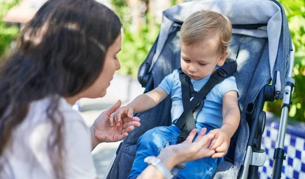 Anne ve oğlu parkta bebek arabasında otururken kendinden emin bir şekilde gülümsüyor.