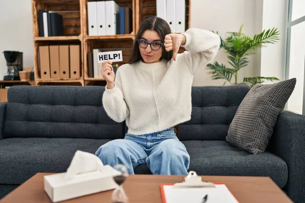 stock image Young hispanic woman going to therapy at consultation office asking for help with angry face, negative sign showing dislike with thumbs down, rejection concept 