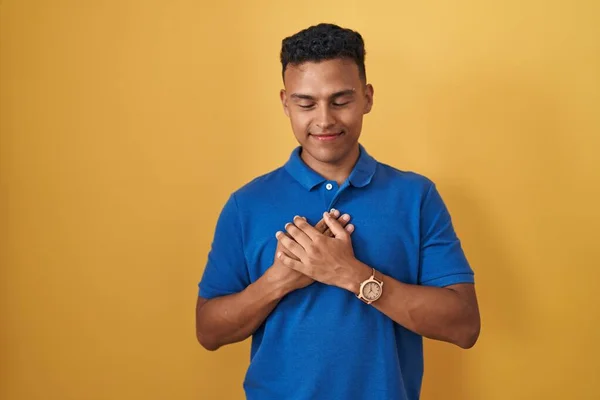 Young Hispanic Man Standing Yellow Background Smiling Hands Chest Closed — Stock Photo, Image