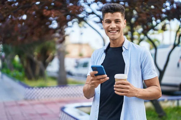 Mladý Hispánec Muž Pomocí Smartphone Pití Kávy Parku — Stock fotografie